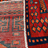 Close-up of rug fringe and side design: white band border with navy and red motifs.