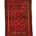Red area rug with navy and orange stepped medallion pattern and cream fringe on edges.