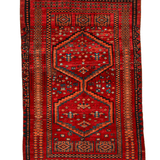 Red area rug with navy and orange stepped medallion pattern and cream fringe on edges.