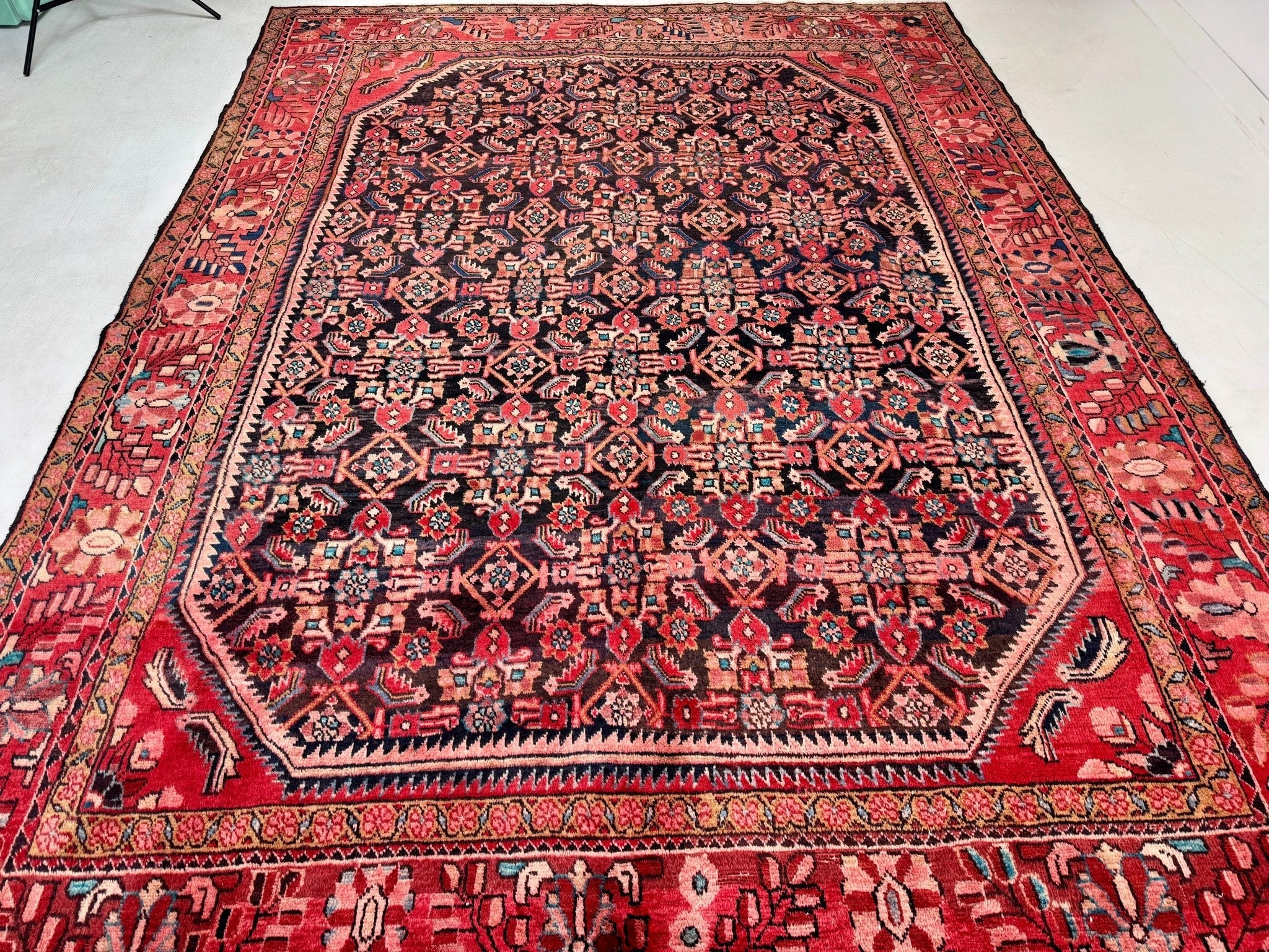 Persian-style area rug with red border and navy central medallion geometric pattern