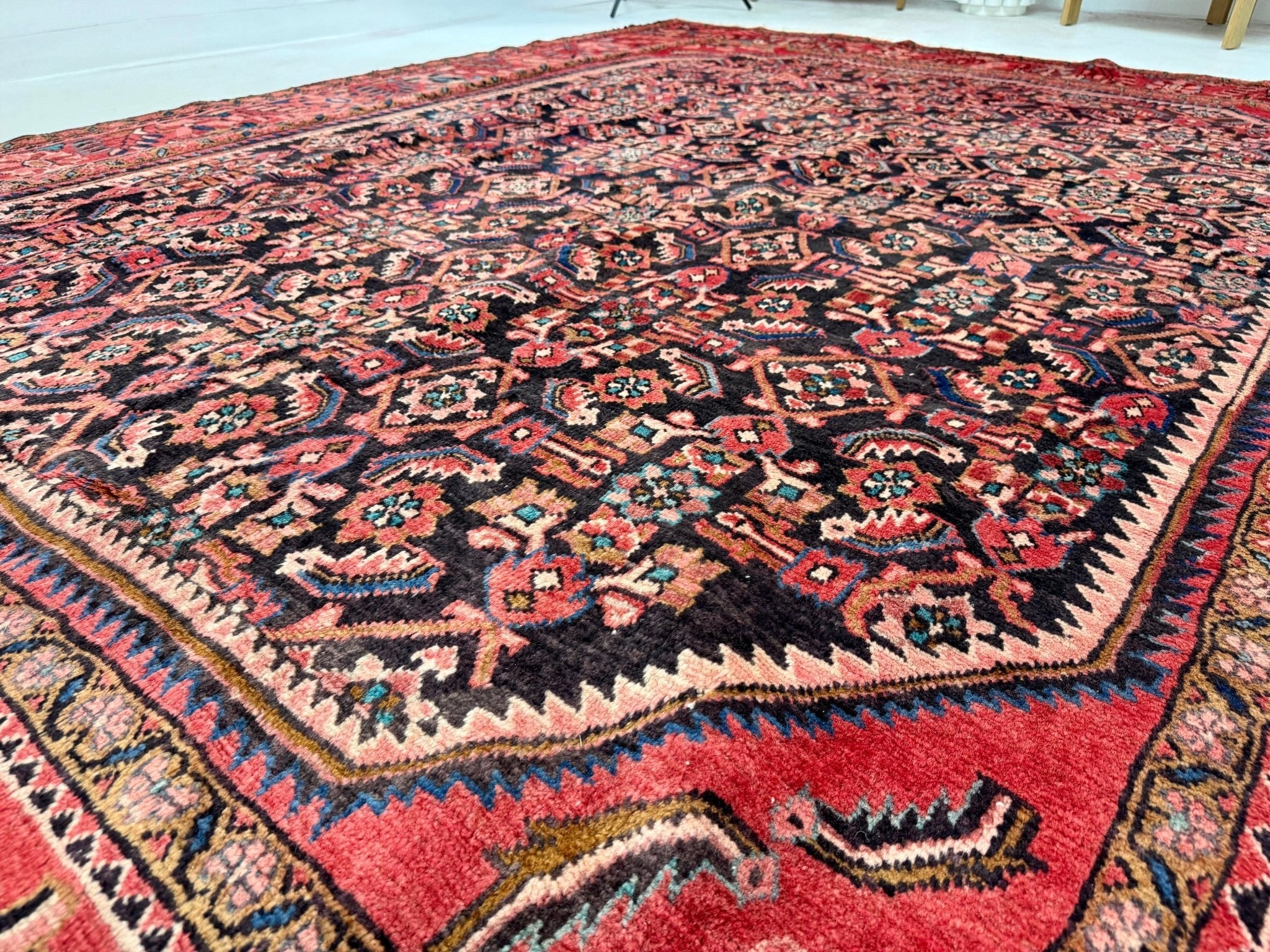 Persian-style patterned rug with red ground and navy geometric field, fringed edges