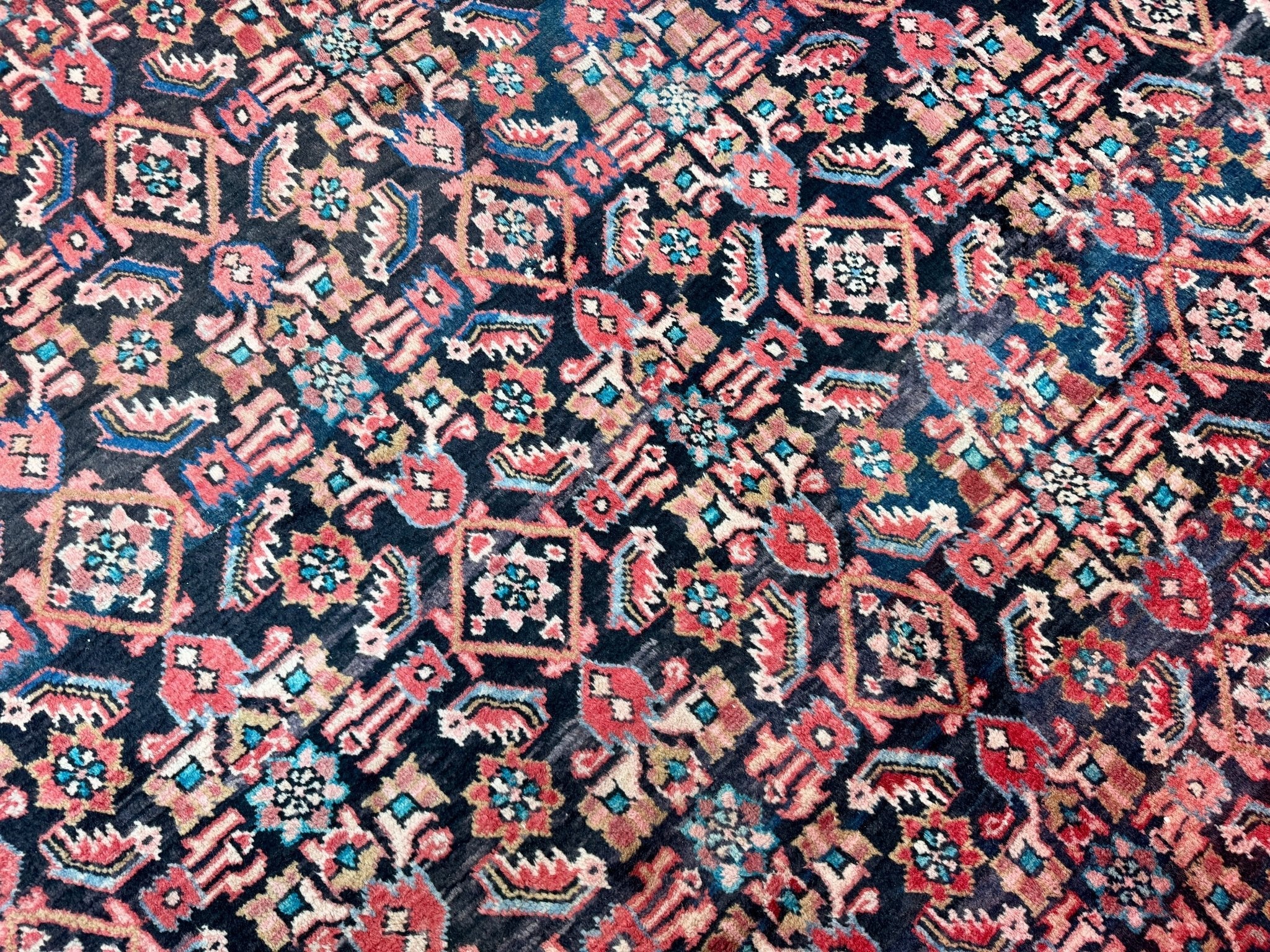 Navy area rug with red and teal geometric motifs and dense patterned texture