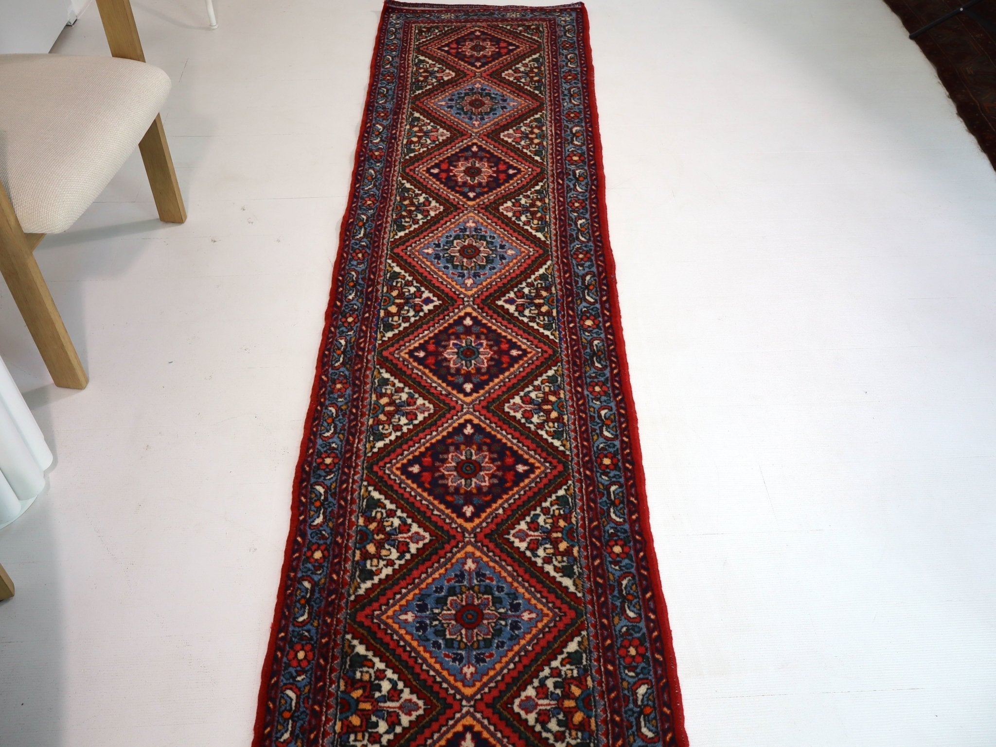 Persian runner rug with red border and central blue diamond medallion pattern