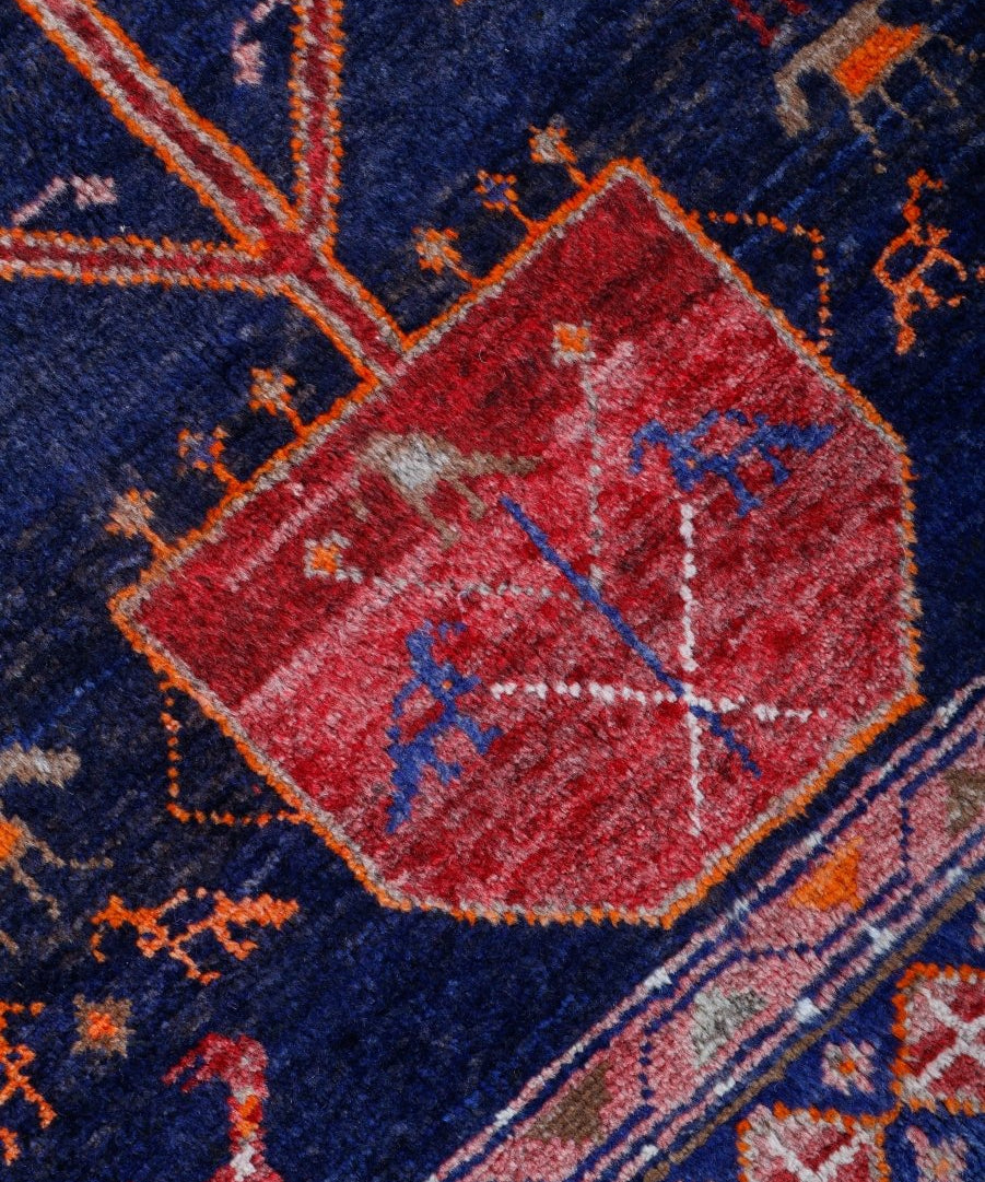 Close-up of navy rug corner with a red diamond motif and multicolor accents