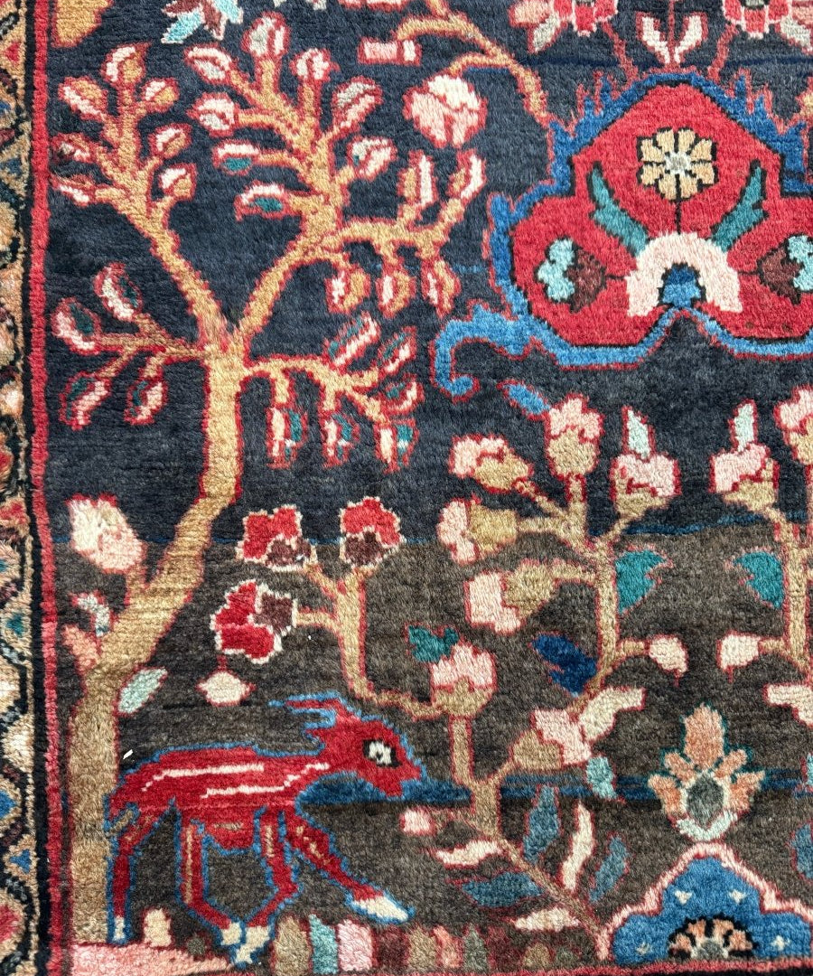Runner rug close-up showing dark navy field with red, teal, and cream floral and bird motifs