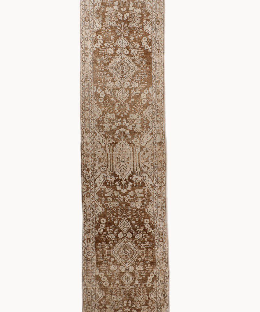 Runner rug with ornate medallion and geometric motifs in tan, beige, and dark brown