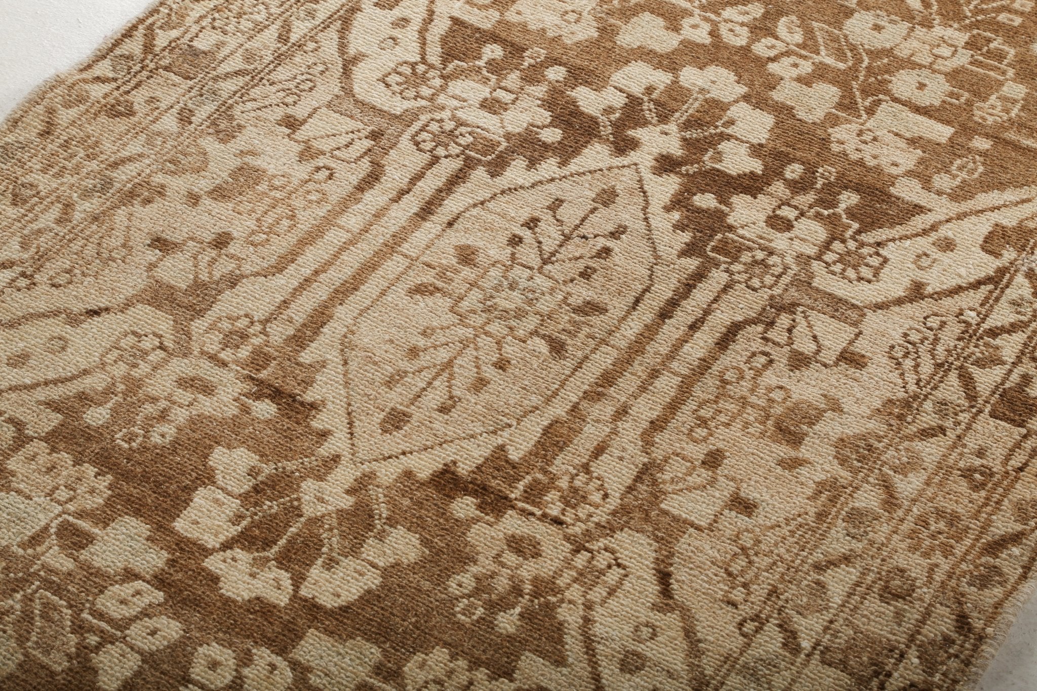 Persian runner rug field with floral and lattice motifs in tan, beige, and dark brown