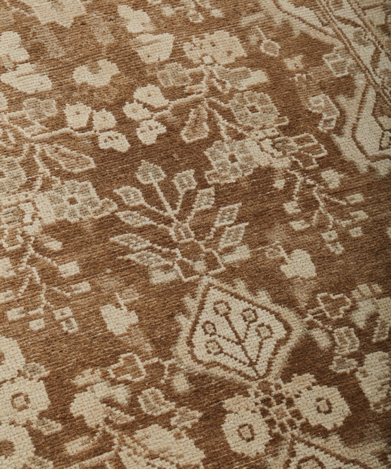 Runner rug pattern close-up featuring stylized flowers and rosettes in beige and brown