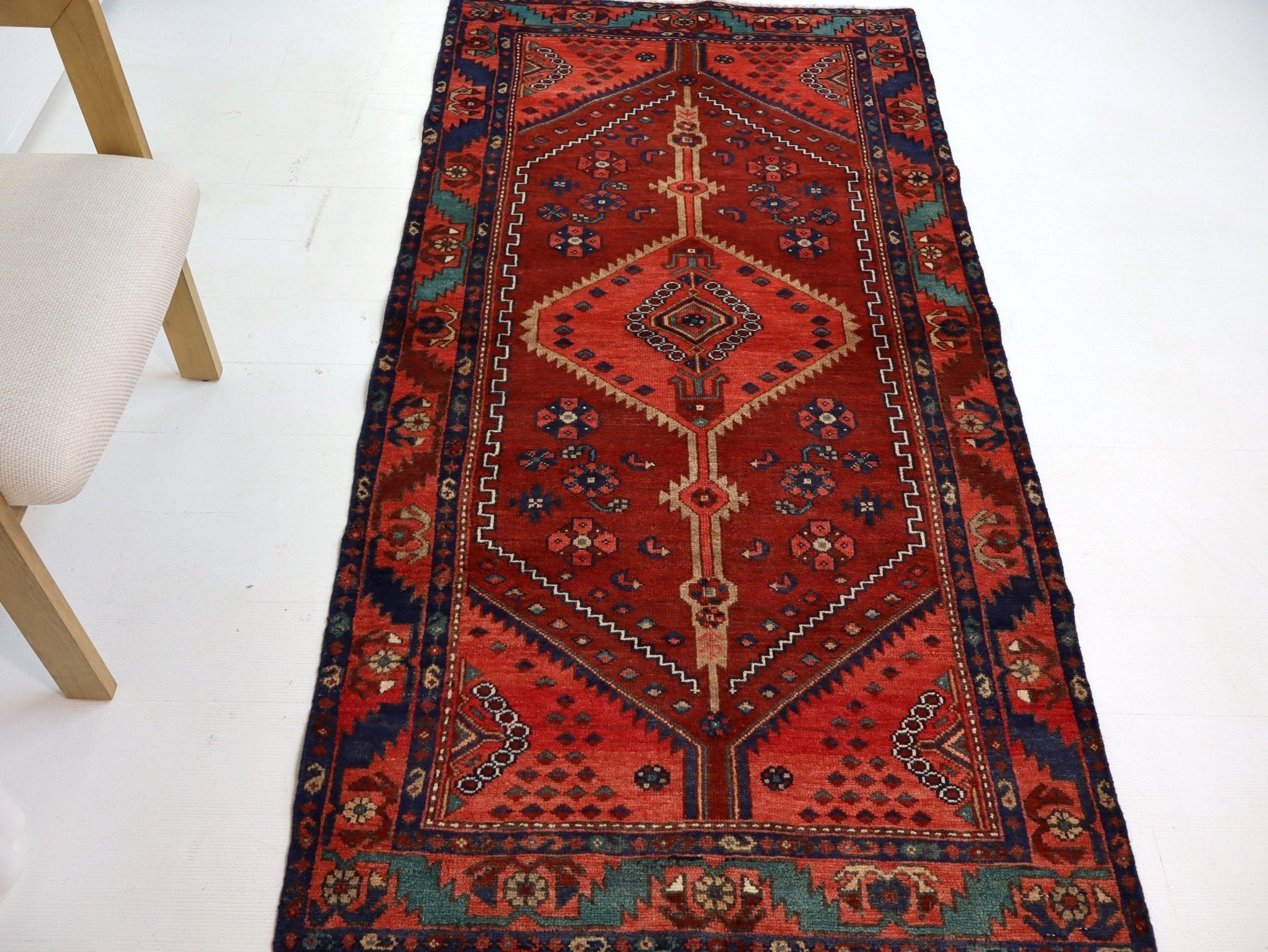 Persian Hamadan runner rug with red field, navy accents, and repeating geometric border.