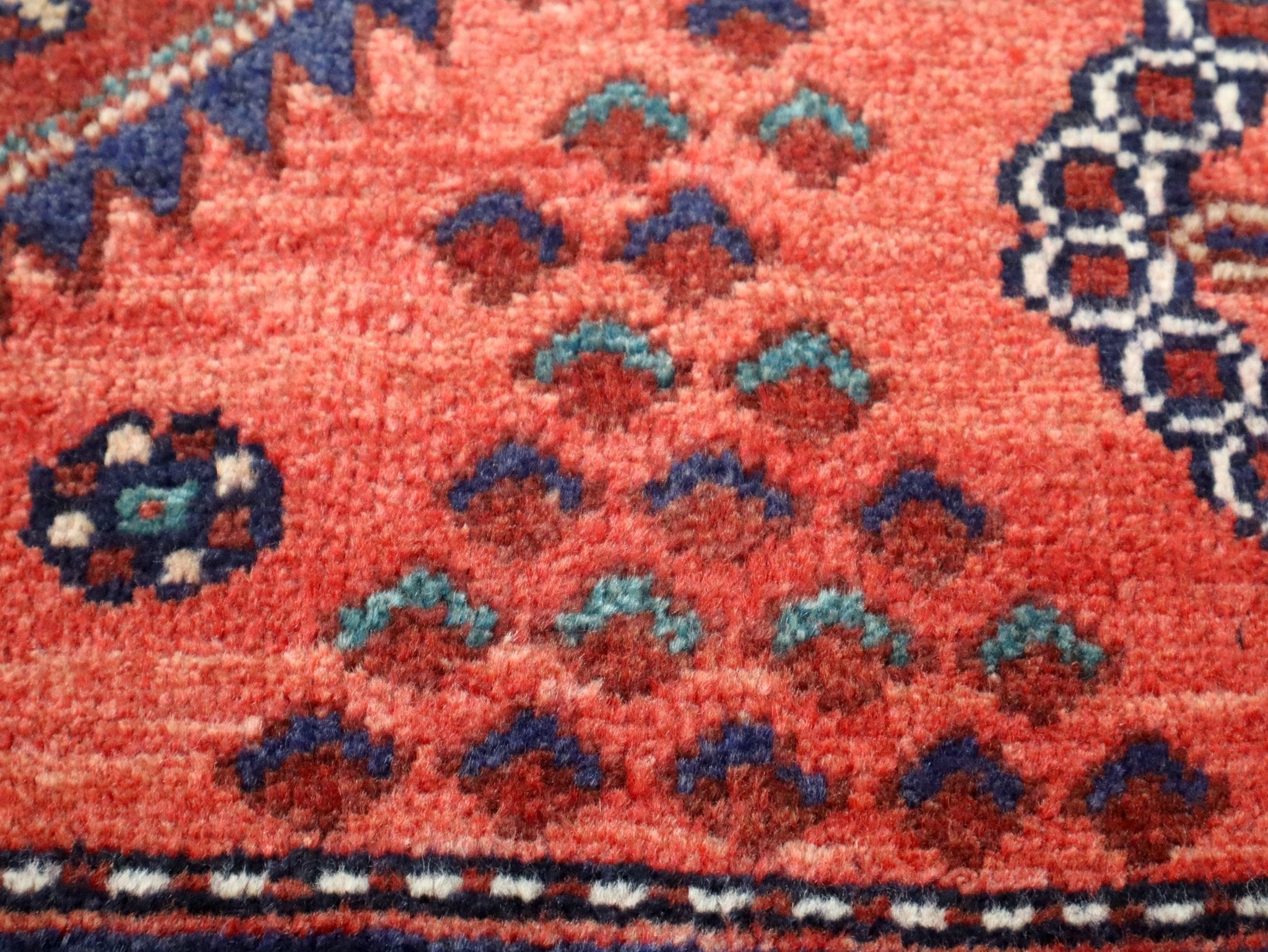 Persian Hamadan runner rug pattern detail: coral-red ground with teal and navy motifs.