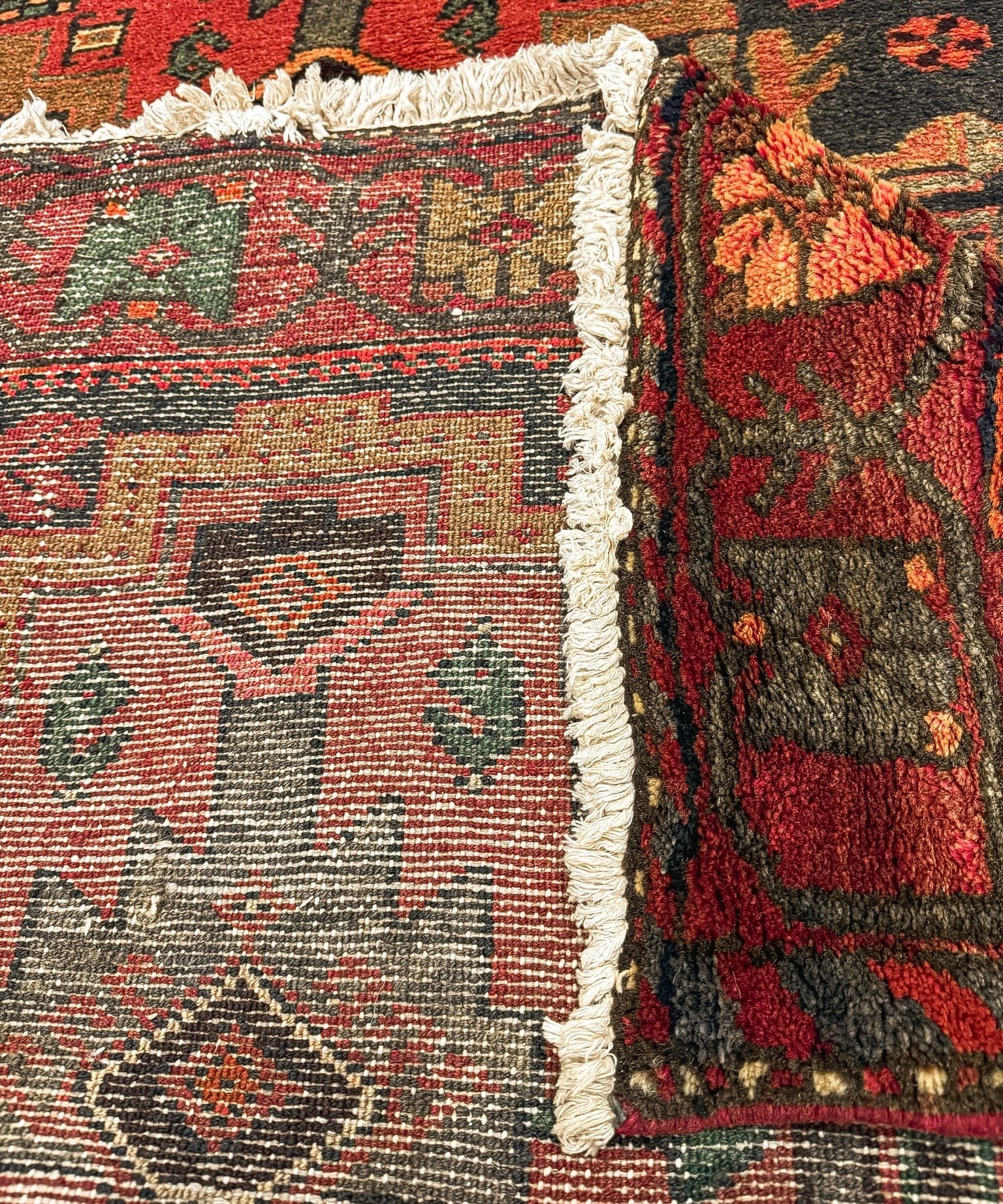 Persian Hamadan runner rug border close-up with dark red and olive motifs and white fringes