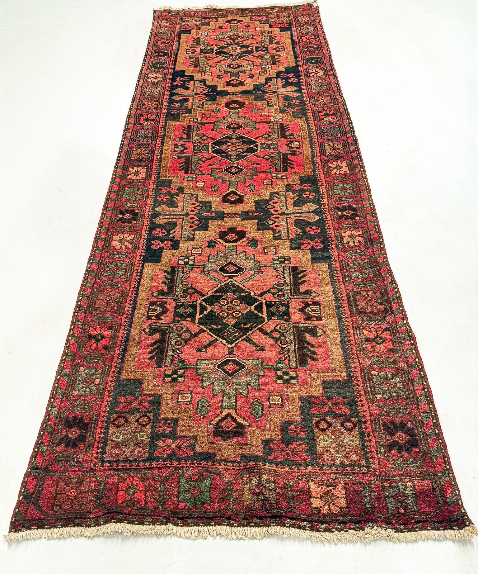 Persian Hamadan runner rug with red, black, and beige geometric medallions and fringed ends