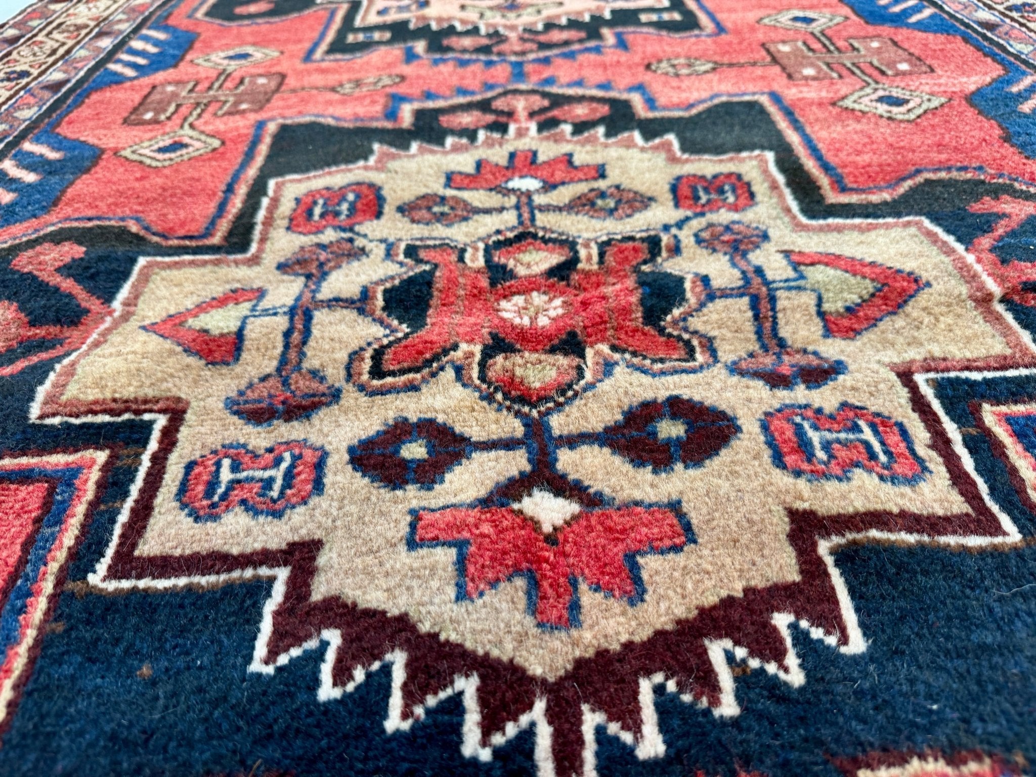 Runner rug close-up of cream floral medallion on red ground with blue accents