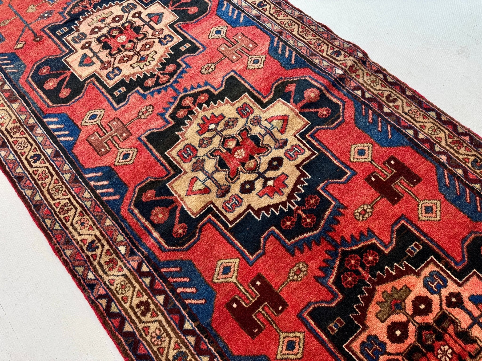 Close-up of red runner rug pattern with blue corner elements and cream detailing