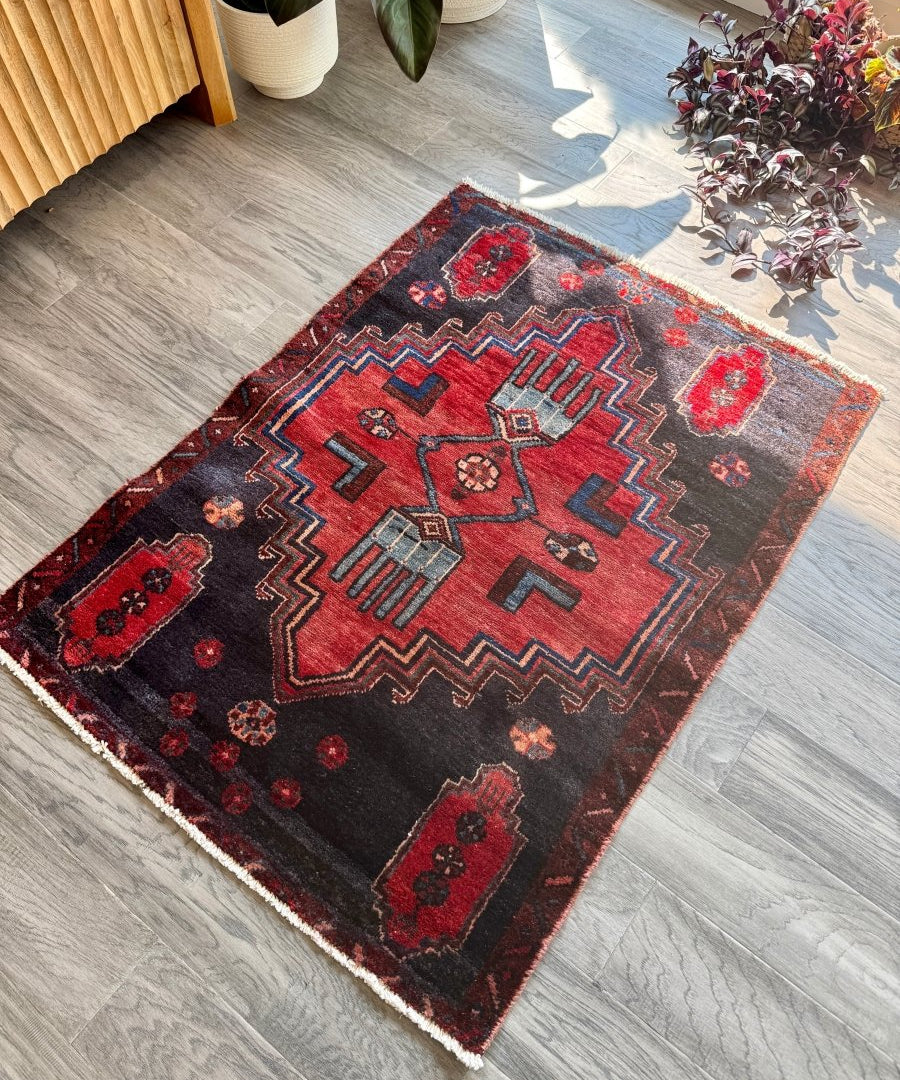 Small Persian-style area rug with red center medallion, gray ground, and zigzag border