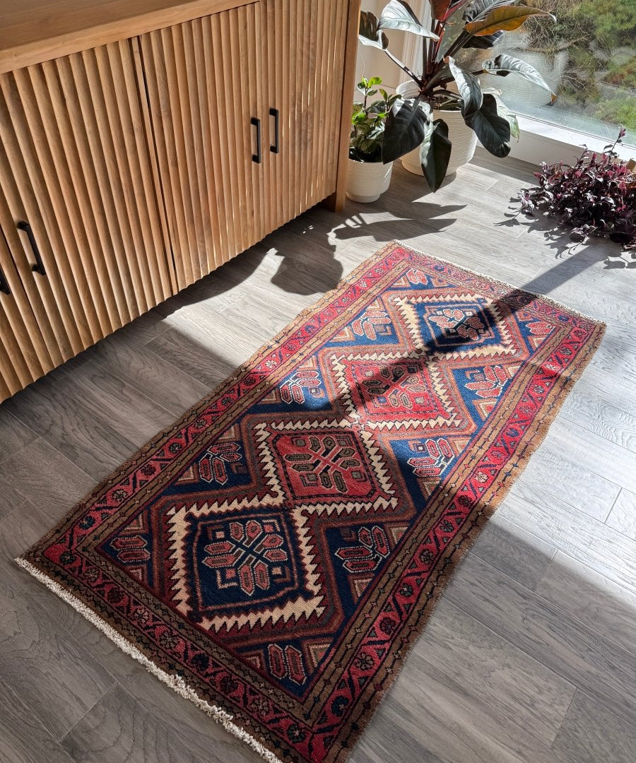 Navy, red, and tan woven rug with diamond medallions and repeating geometric border.