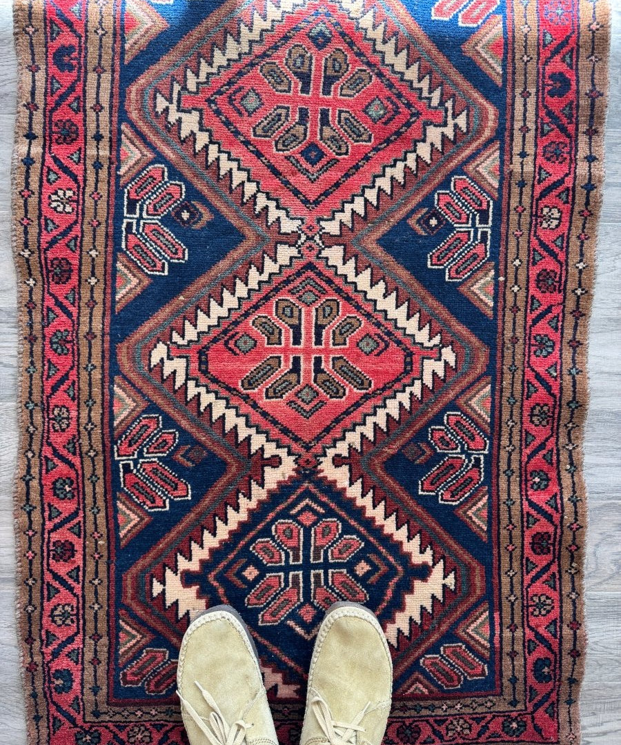 Blue, red, and tan woven rug with diamond central medallion and geometric border.