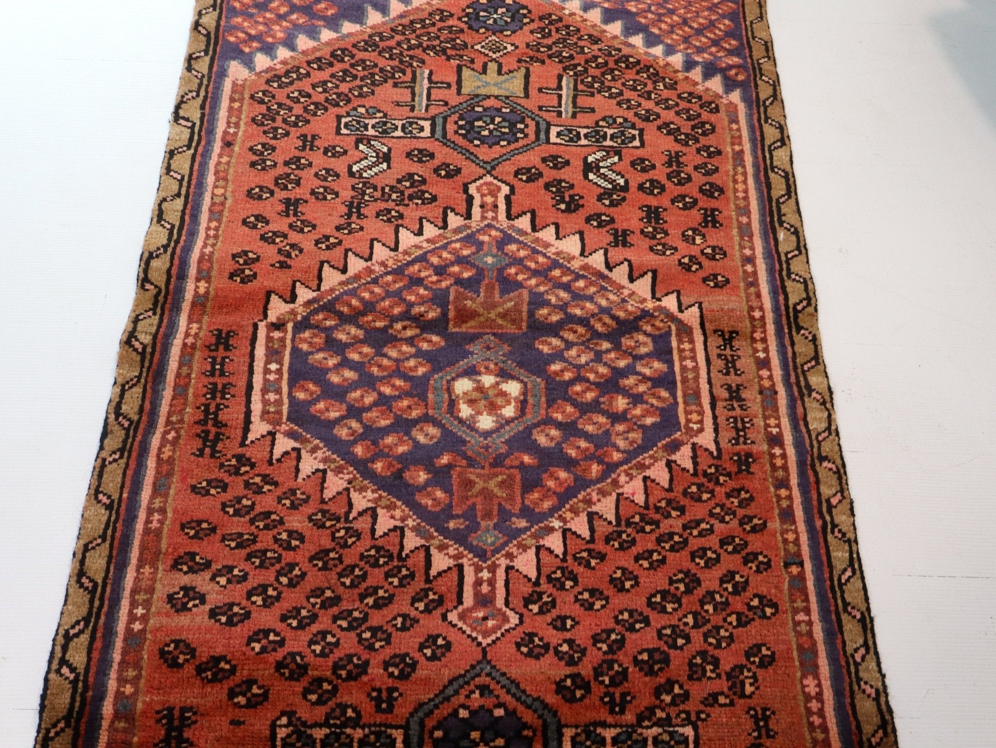 Persian Hamedan-style rug with rust red field, navy corner motifs, and diamond medallion