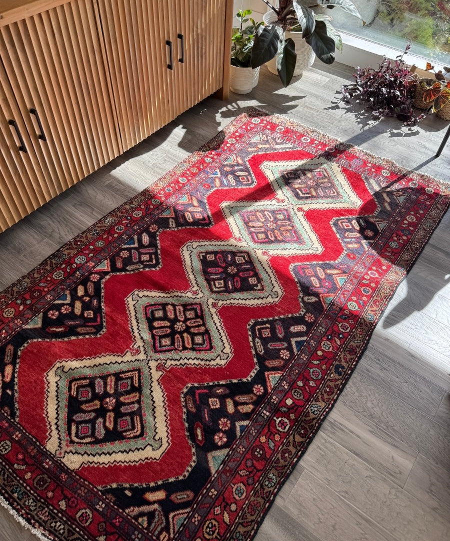 Persian Hamedan rug with red ground, navy border, and repeating cream diamond medallions