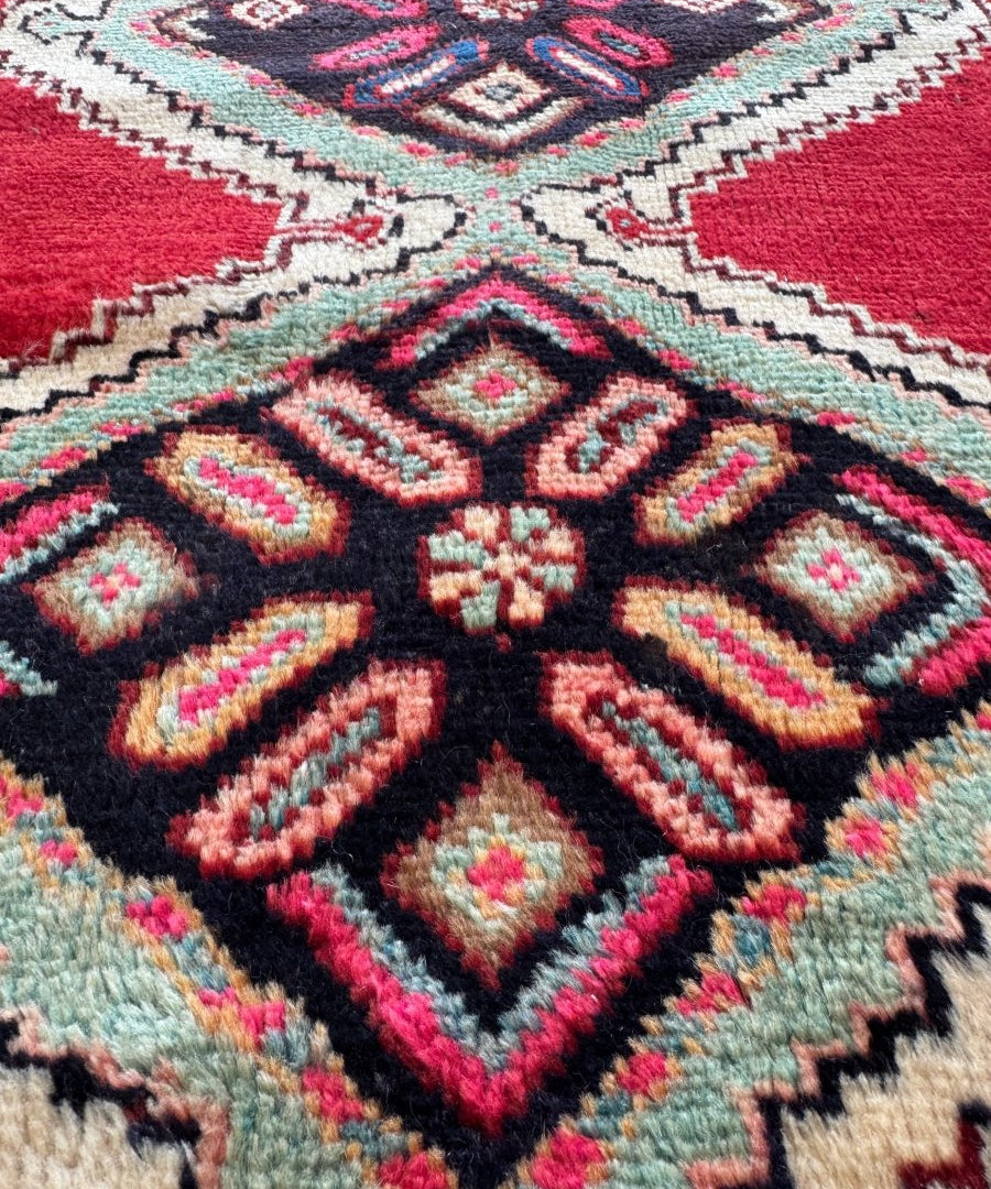 Persian Hamedan rug close-up with red field and black center diamond medallion