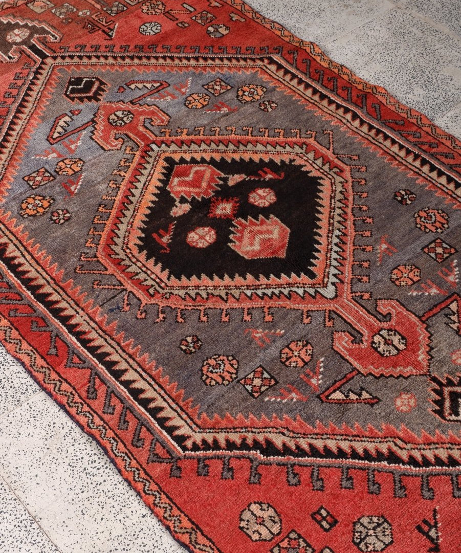 Persian Zanjan rug corner detail with red trim, gray field, and black-and-red medallion