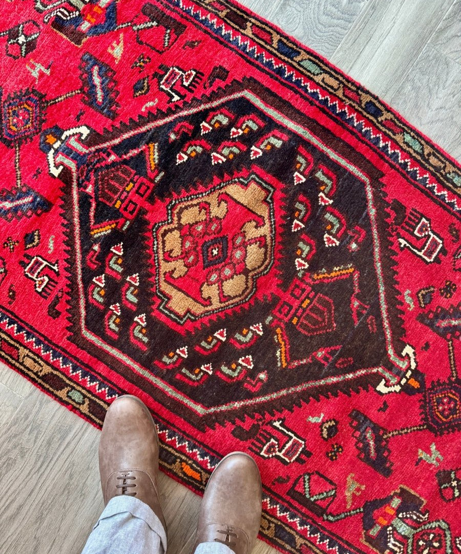 Red Persian Hamedan runner rug close-up with navy, teal, and gold geometric designs
