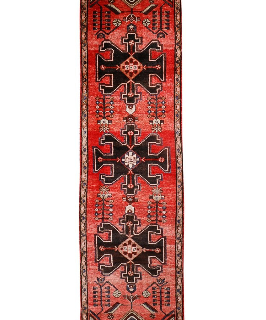 Runner rug with red, black, and beige geometric medallions and border trim.