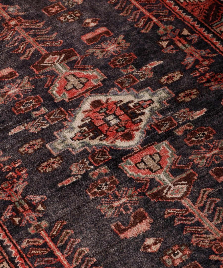 Close-up of Persian Hamadan runner rug: dark navy ground with red, cream, and angular motifs