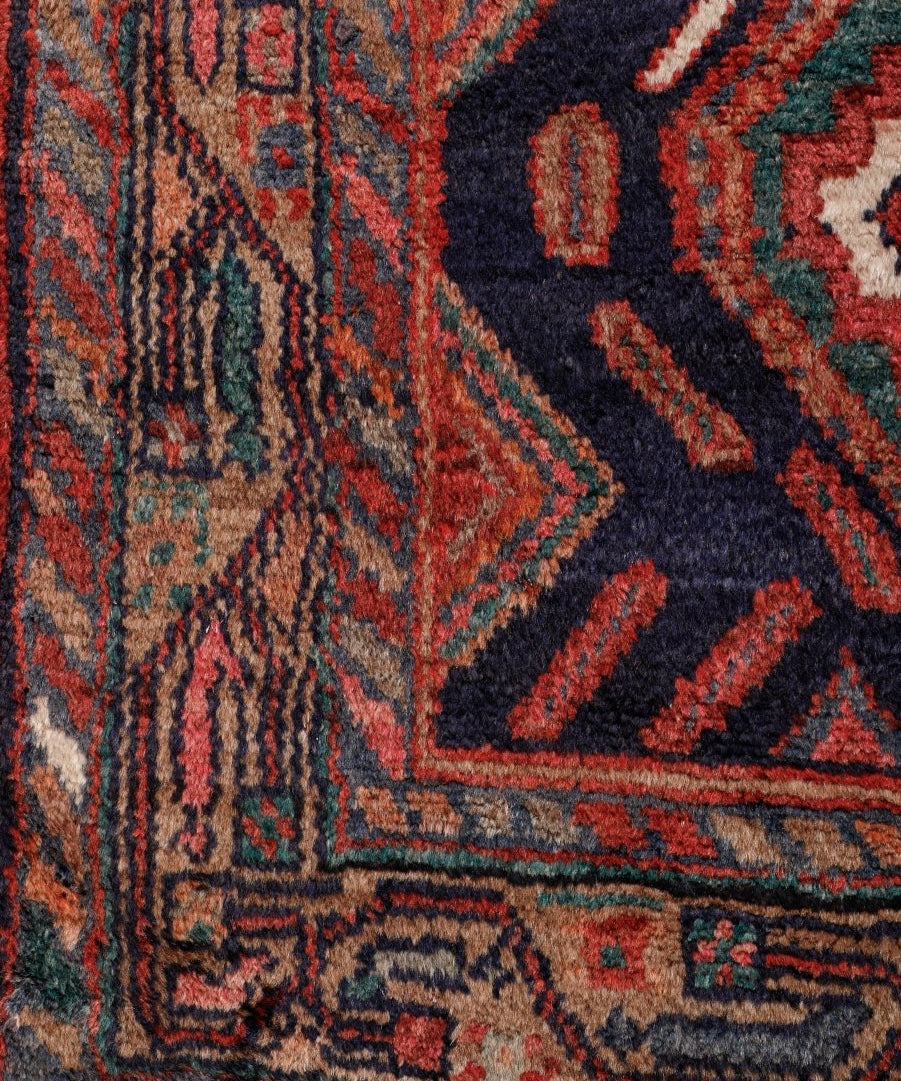 Close-up of Persian Hamadan runner rug with navy ground and rust geometric motifs