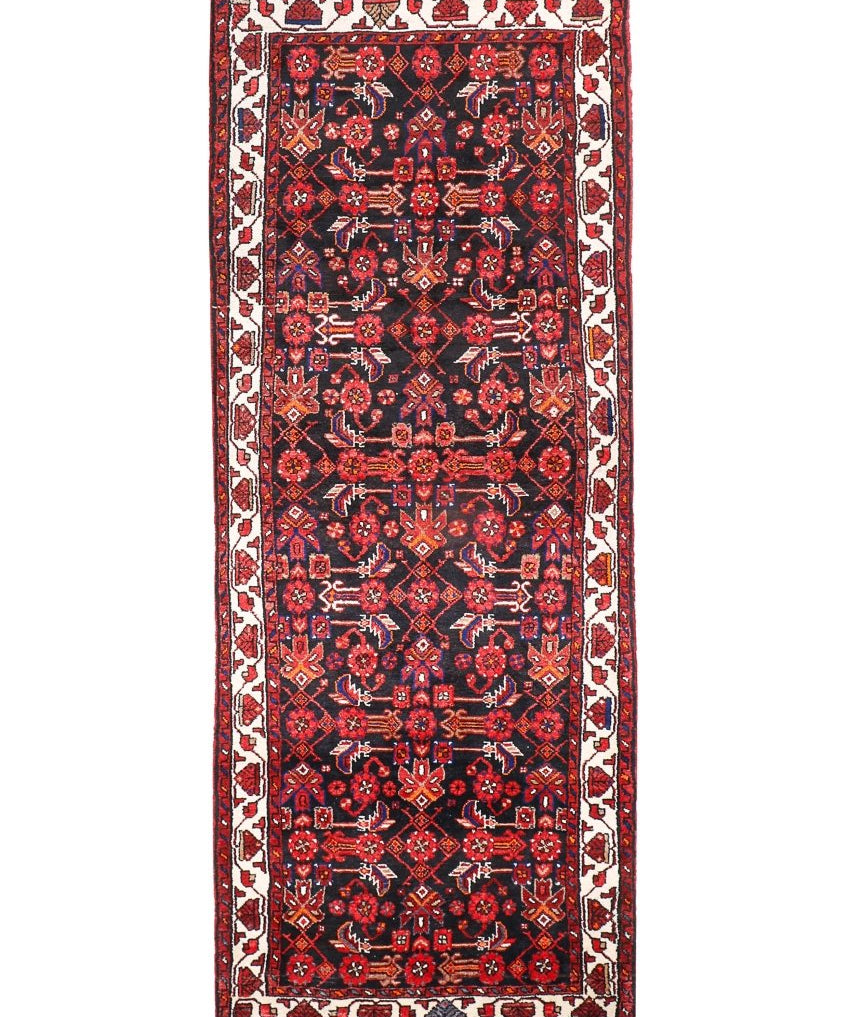 Persian runner rug with dark red medallion pattern, black field, cream border stripes