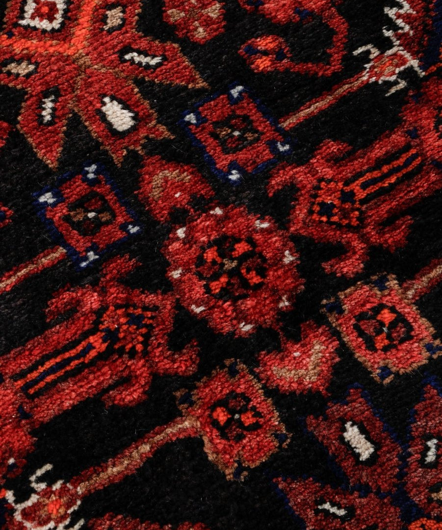 Persian runner rug pattern close-up in dark red, black, and cream with small blue details