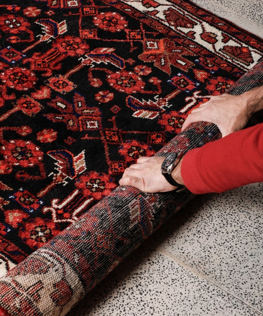 Persian runner rug close-up showing dark red and black pattern with cream accents
