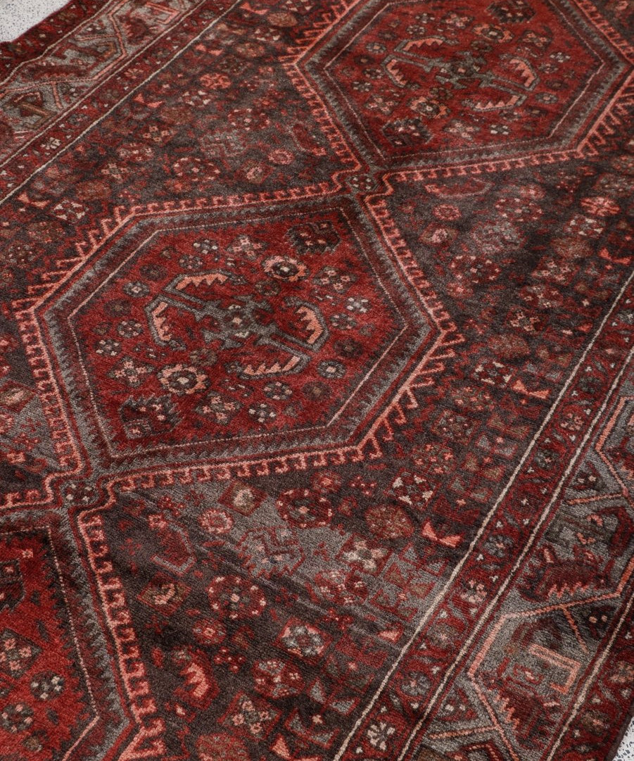 Persian Hamedan runner rug close-up showing red geometric panels and fine trim edging.