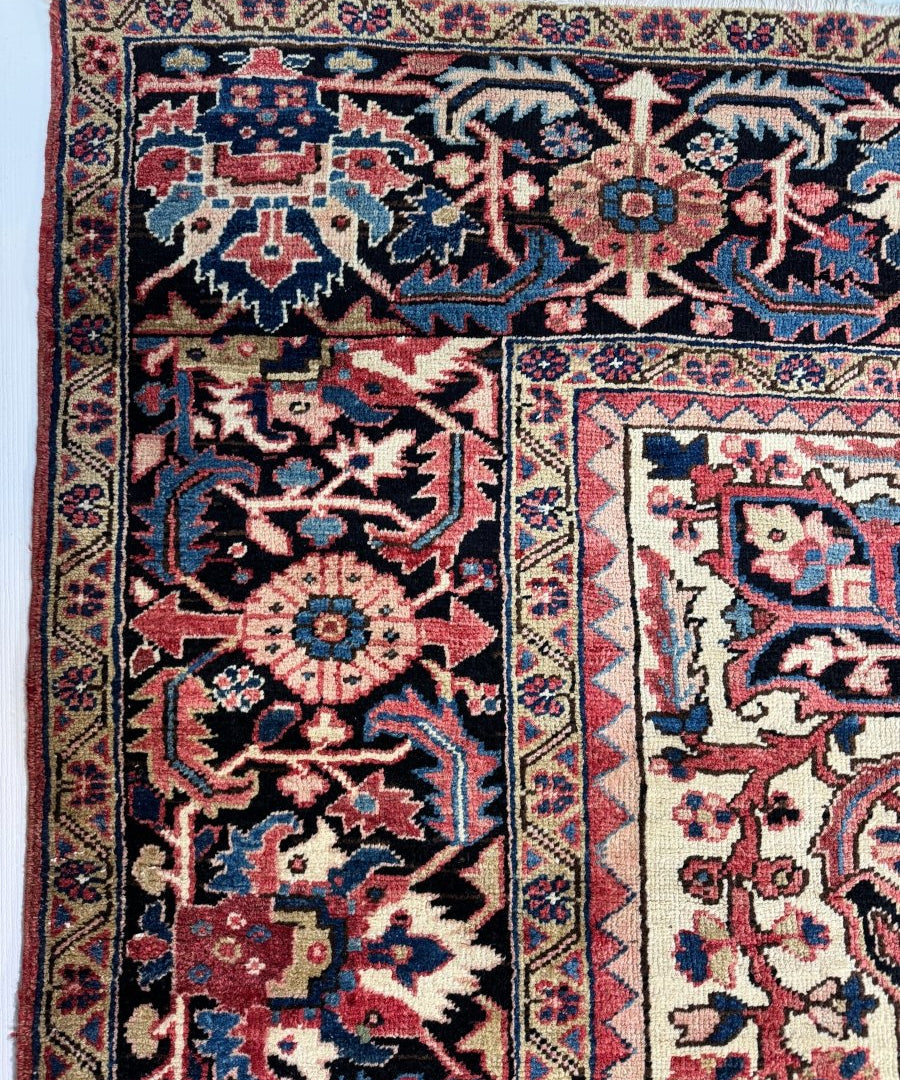 Persian Heriz rug close-up showing geometric pattern in red, navy, blue, and cream