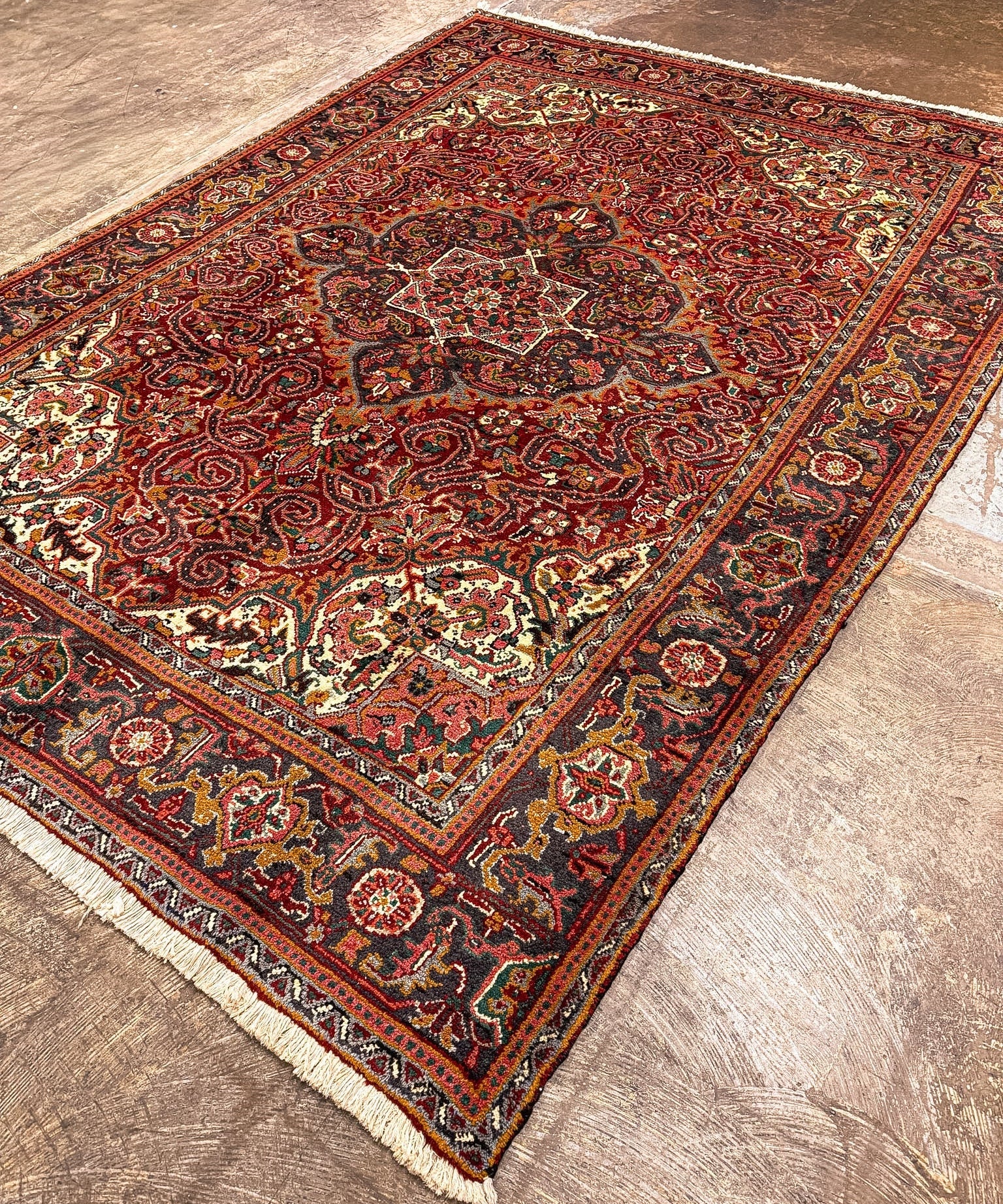 Heriz rug with red and navy geometric floral pattern, cream border, short fringe