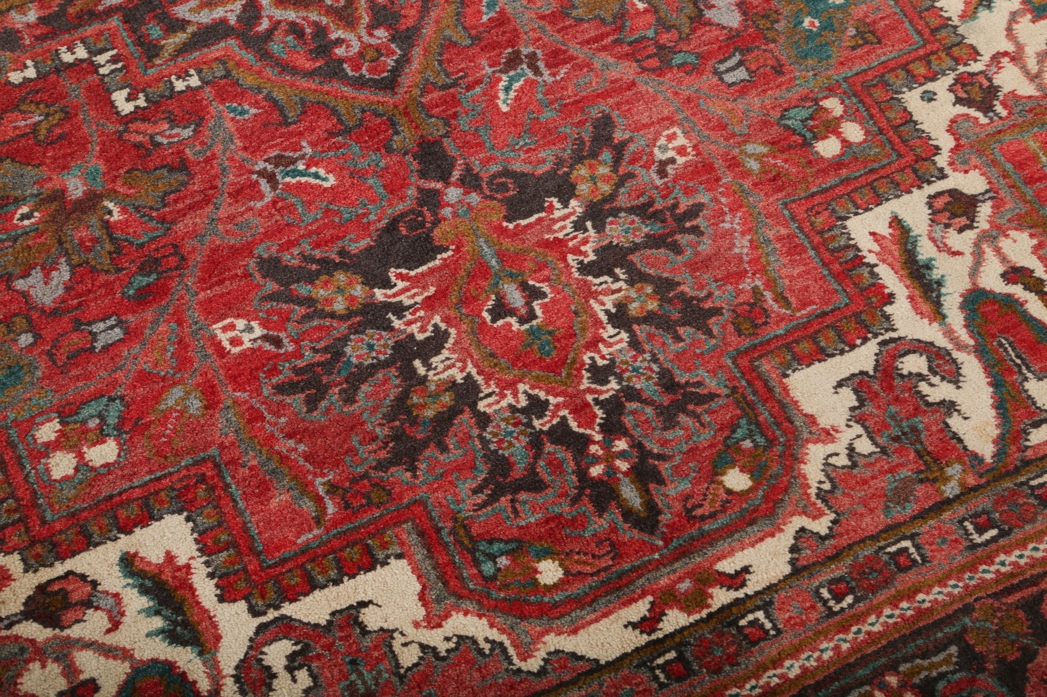 Persian Heriz style rug corner detail with red background, dark motifs, and cream highlights