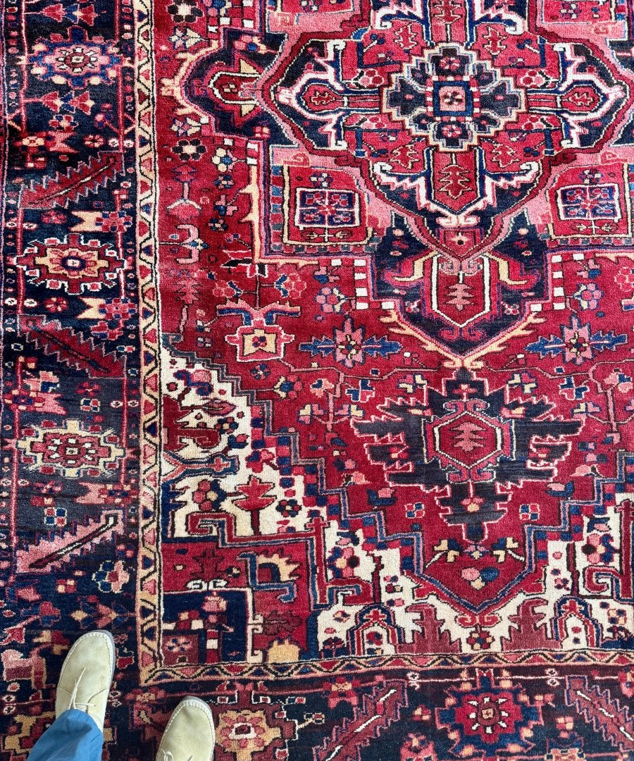 Persian Heriz rug with red field, navy accents, and geometric medallion motifs.