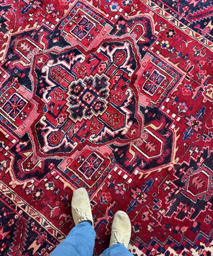 Persian Heriz rug close-up with red ground, navy outlines, and ornate floral geometric patterns.