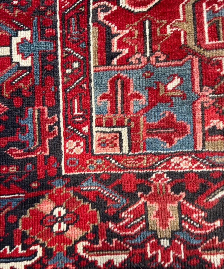 Close-up of red Persian rug with navy and cream geometric motifs