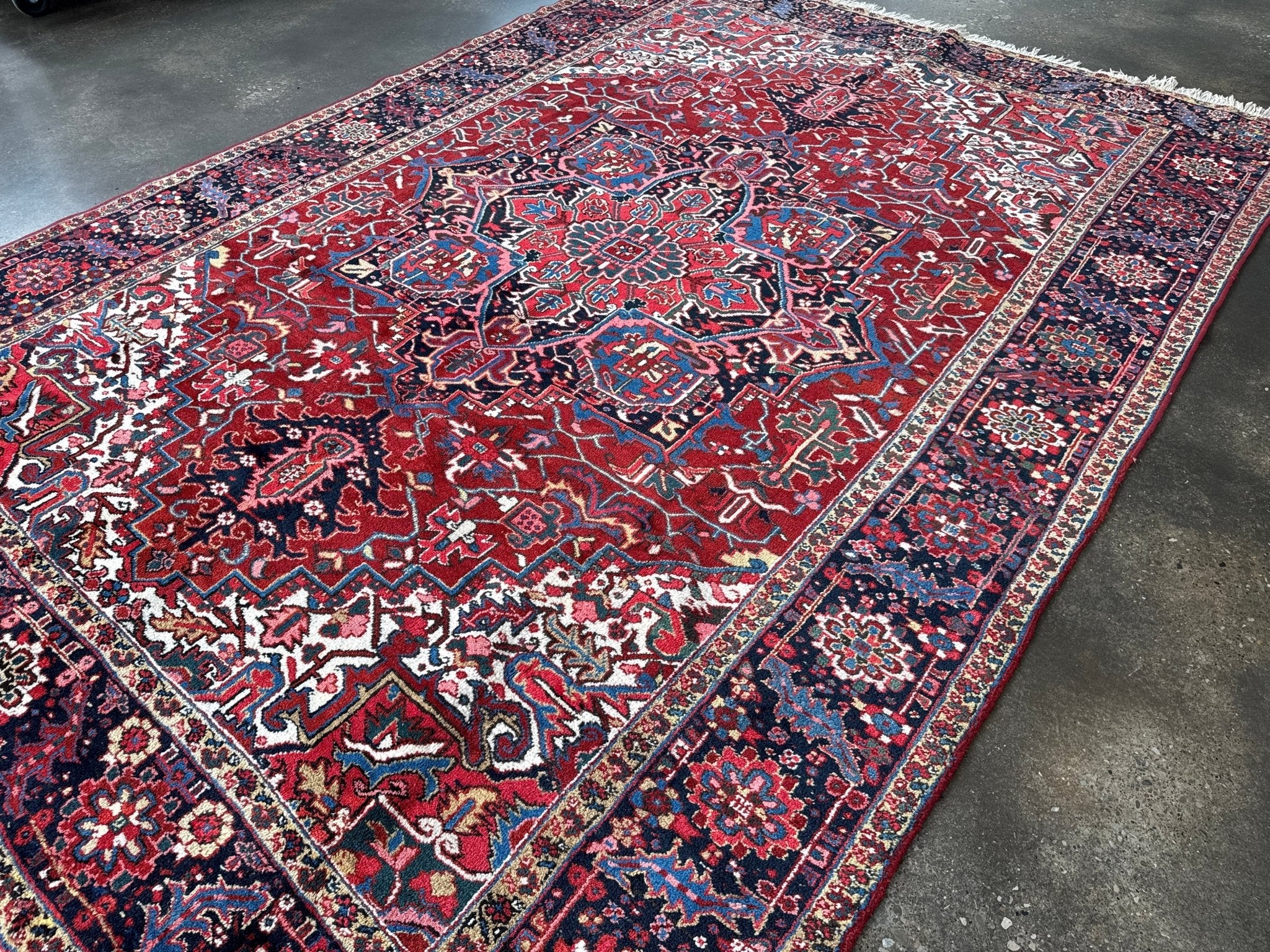 Red and navy Persian-style rug with ornate medallion and wide border with motifs.