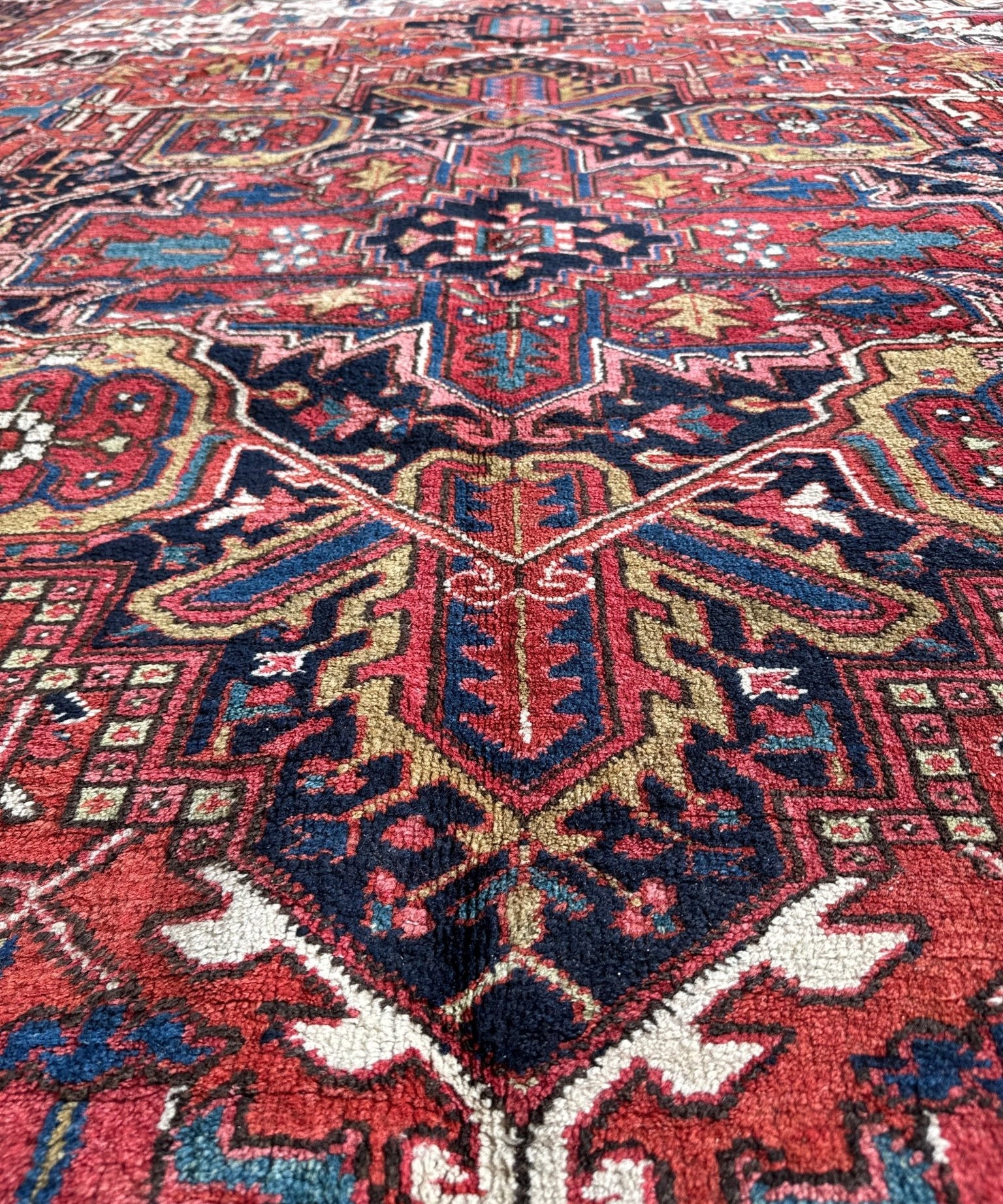 Close-up Heriz rug showing red field with navy, blue, and ivory geometric motifs