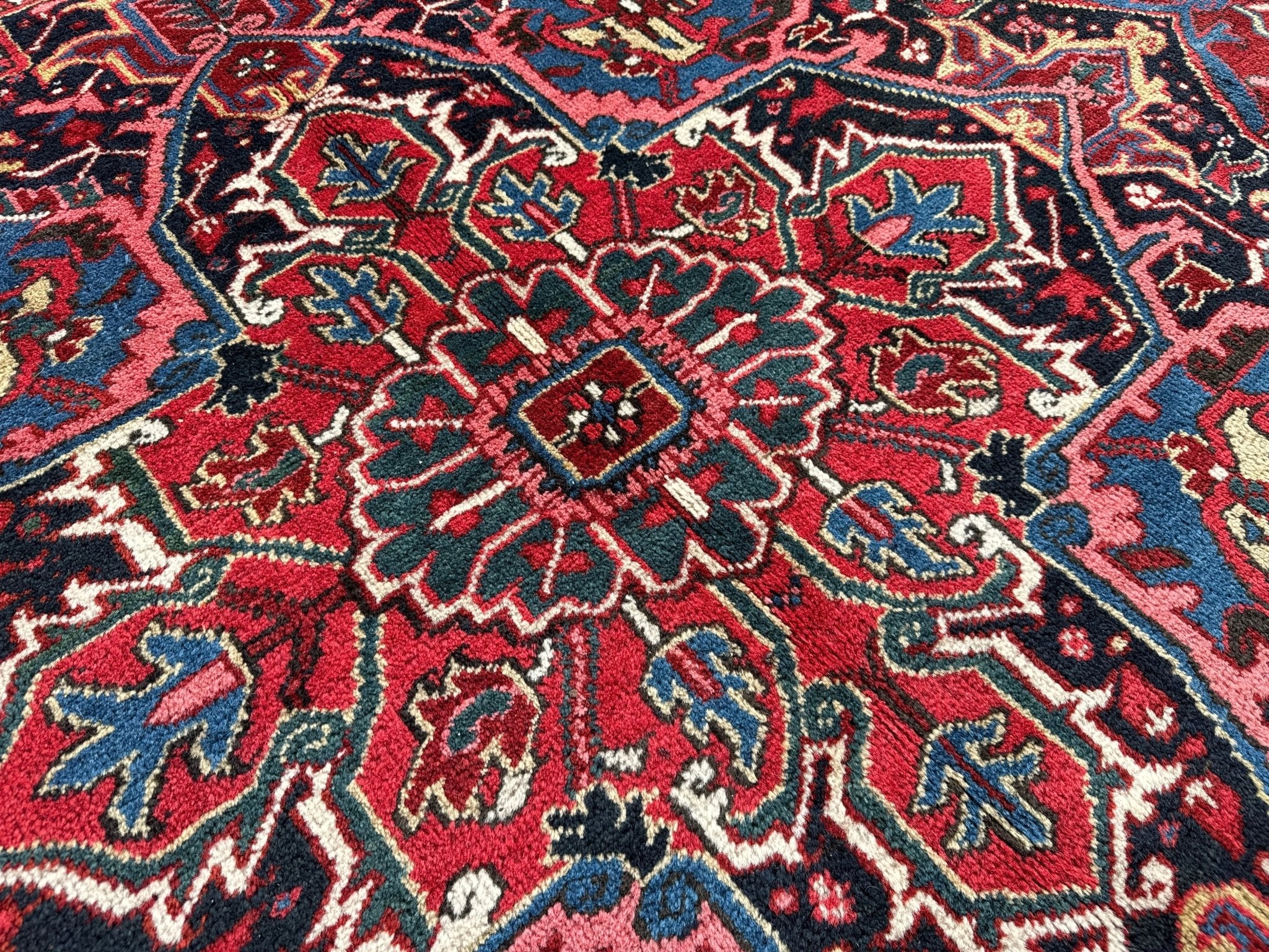 Red and navy Persian-style rug with repeating floral and vine-like pattern details.