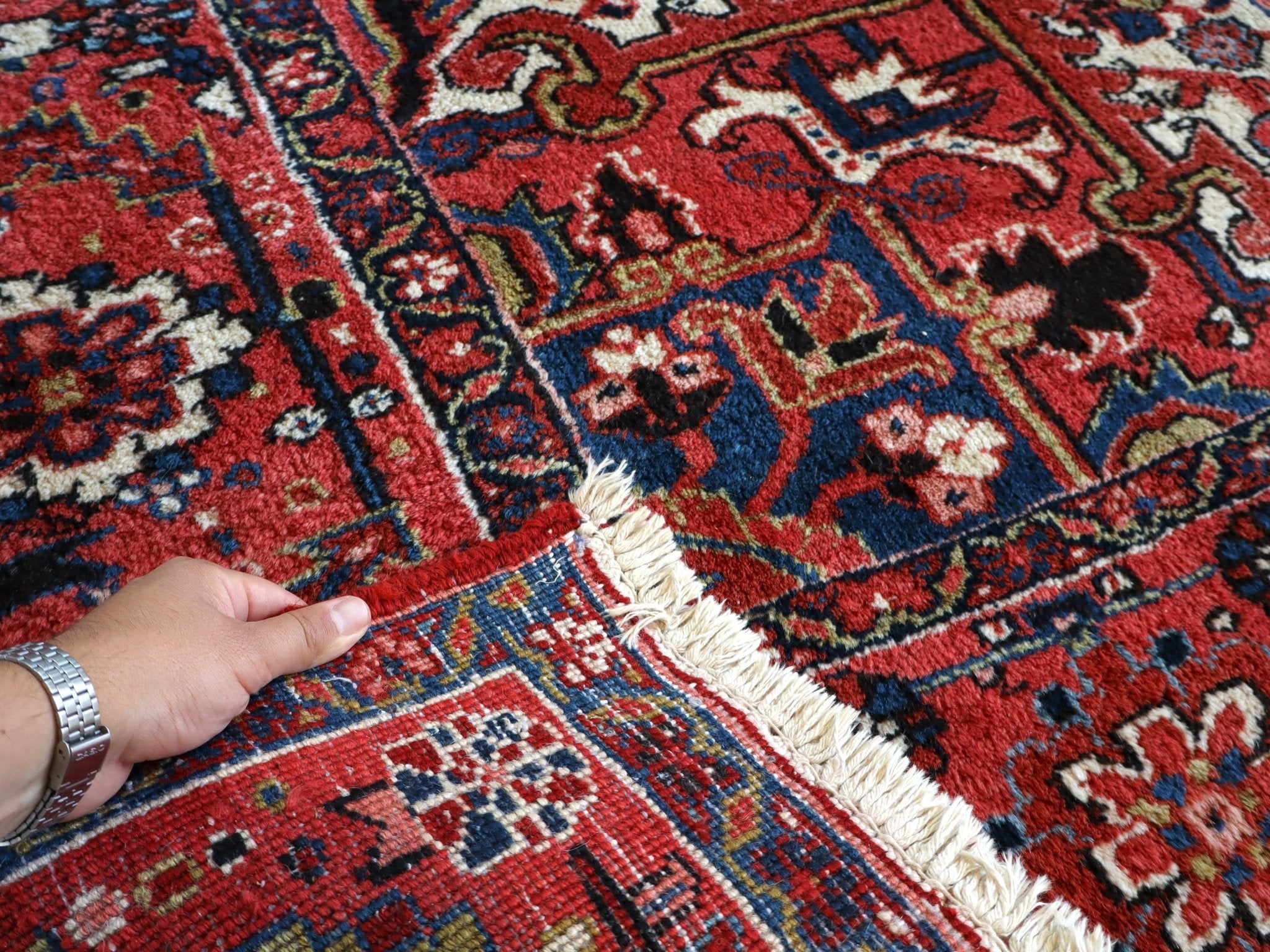 Heriz rug edge with cream fringe, red and blue mosaic pattern, close-up