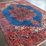 Persian Heriz rug close view with blue field, red patterns, and detailed border edging