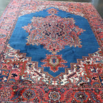 Persian Heriz rug with blue field, red border, and central geometric medallion