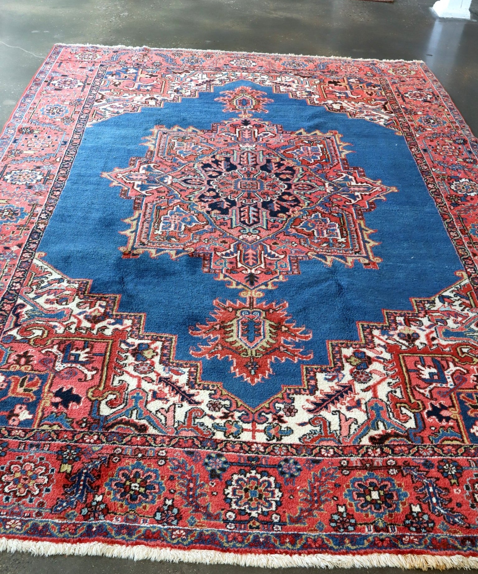 Persian Heriz rug with blue field, red border, and central geometric medallion
