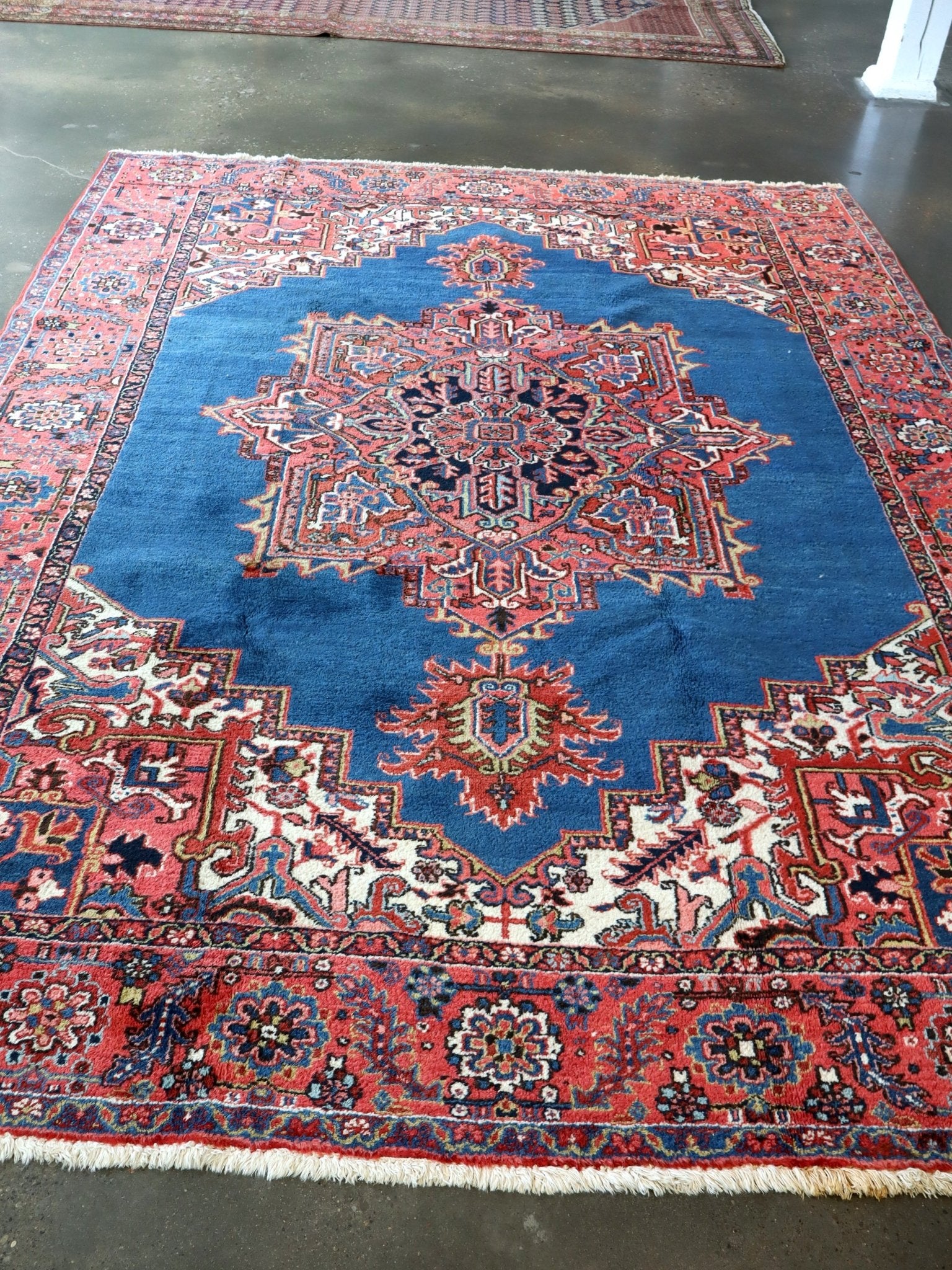 Persian Heriz rug with blue field, red border, and central geometric medallion