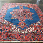 Persian Heriz rug with blue center, red outer border, and repeating corner motifs