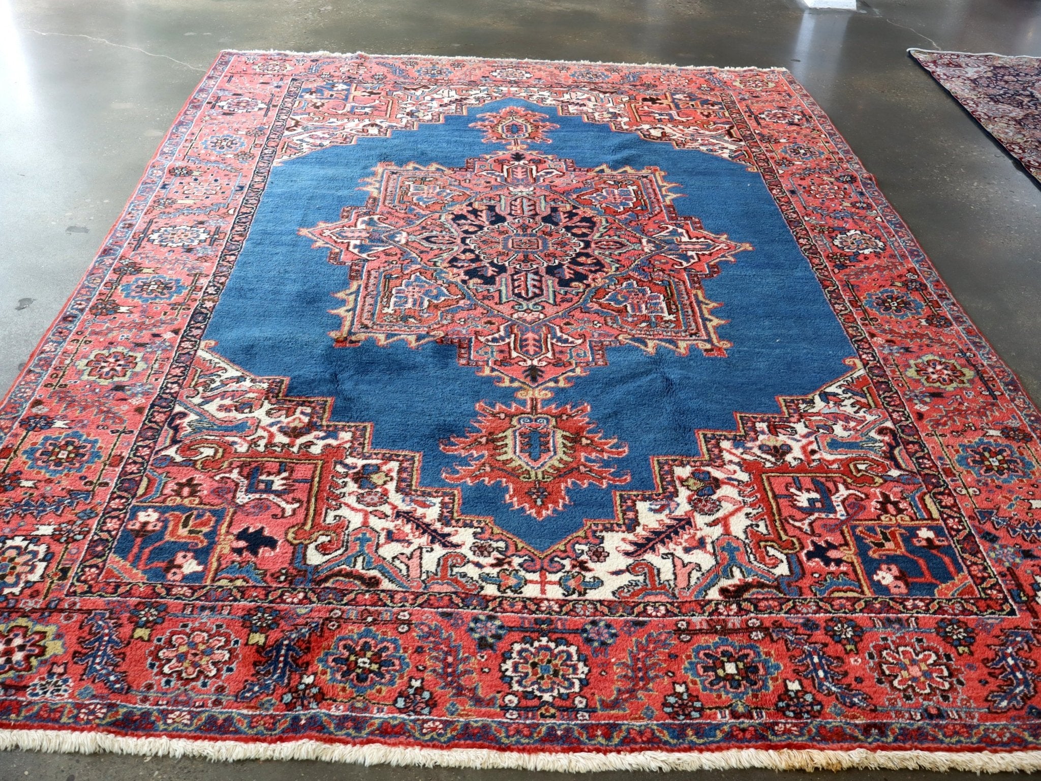 Persian Heriz rug with blue center, red outer border, and repeating corner motifs