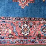 Persian Heriz rug border detail with red and cream medallions on blue background